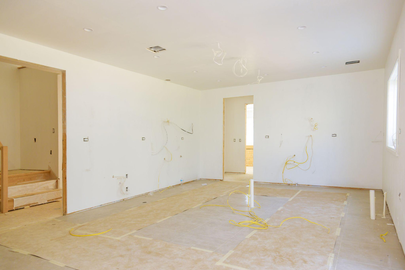 An empty room prepared for a home renovation with wires exposed, demonstrating the importance of clearing the space before work begins.