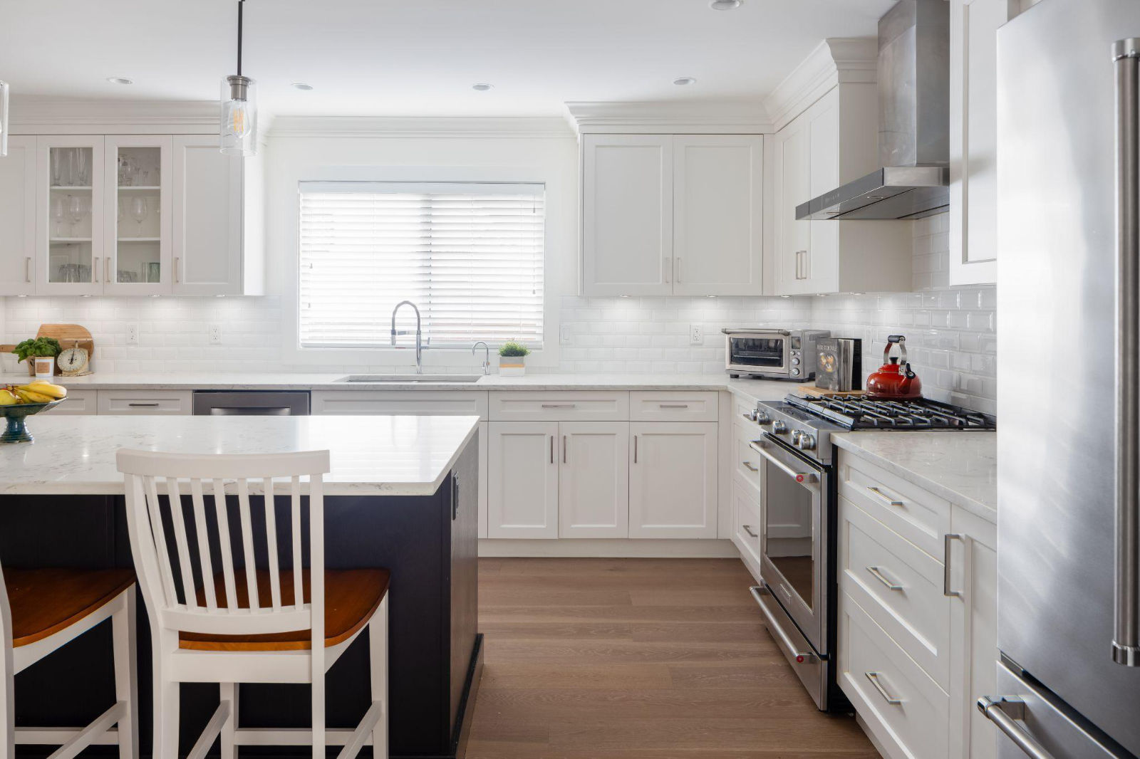 An open-concept renovated white kitchen highlighting strong contractor-client communication with high-end finishes, a large island, and subway tile backsplash.