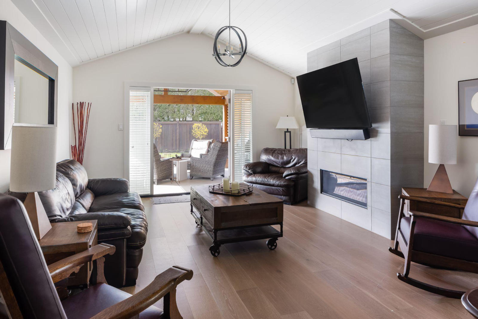 A bright, modern living room with a vaulted ceiling, grey tiled fireplace, and leather seating, showing a stress-free custom home renovation environment.