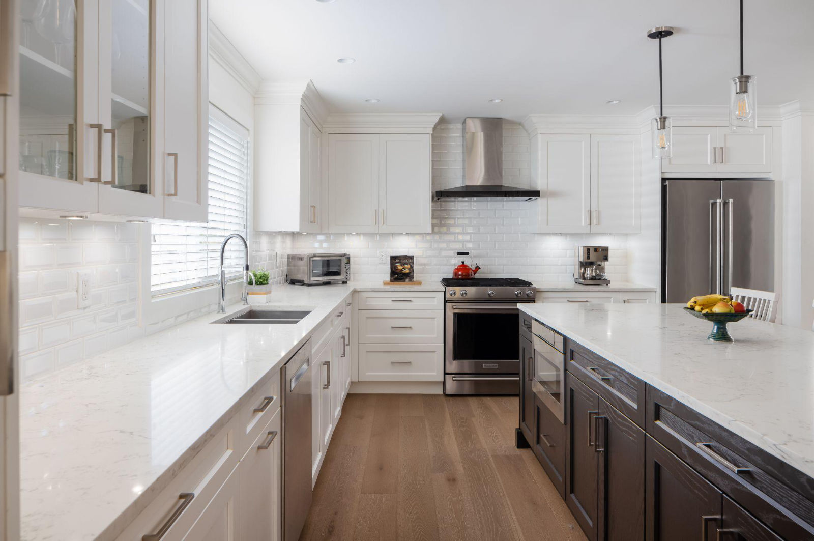 A wide-angle view of a bright, clean luxury kitchen with white cabinetry and a dark wood island, illustrating transparent construction management and planning.