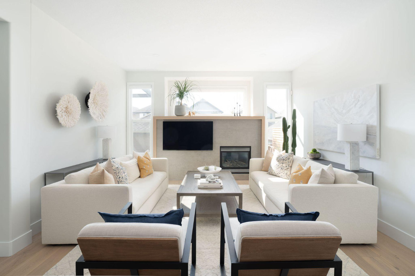 Symmetrical layout of an open-concept living room with twin neutral sofas, armchairs, and a built-in media wall.