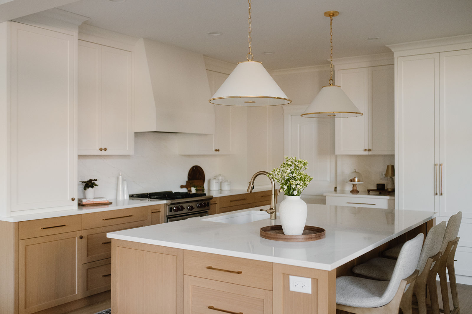 Modern open-concept kitchen island with white countertops and gold pendant lighting after a successful home renovation.