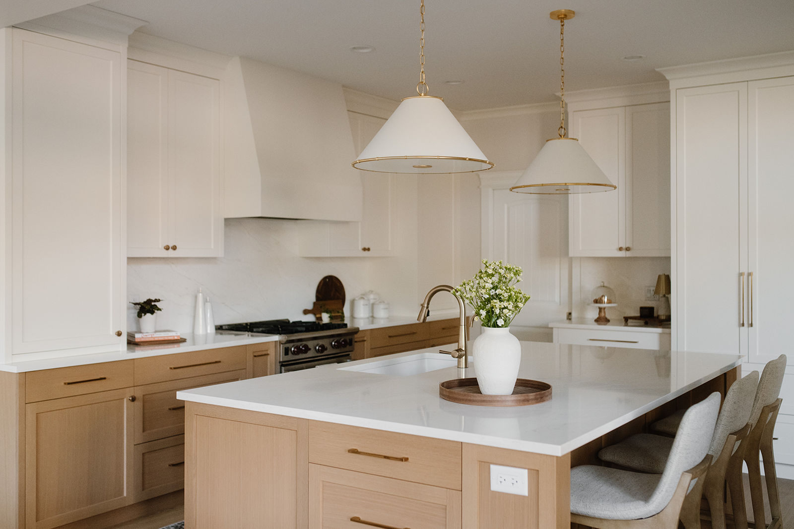 modern-kitchen-layout-ideas-surrey-home Modern custom kitchen featuring a large wooden island with seating, white quartz counter, brass faucet, and stylish white pendant lights.