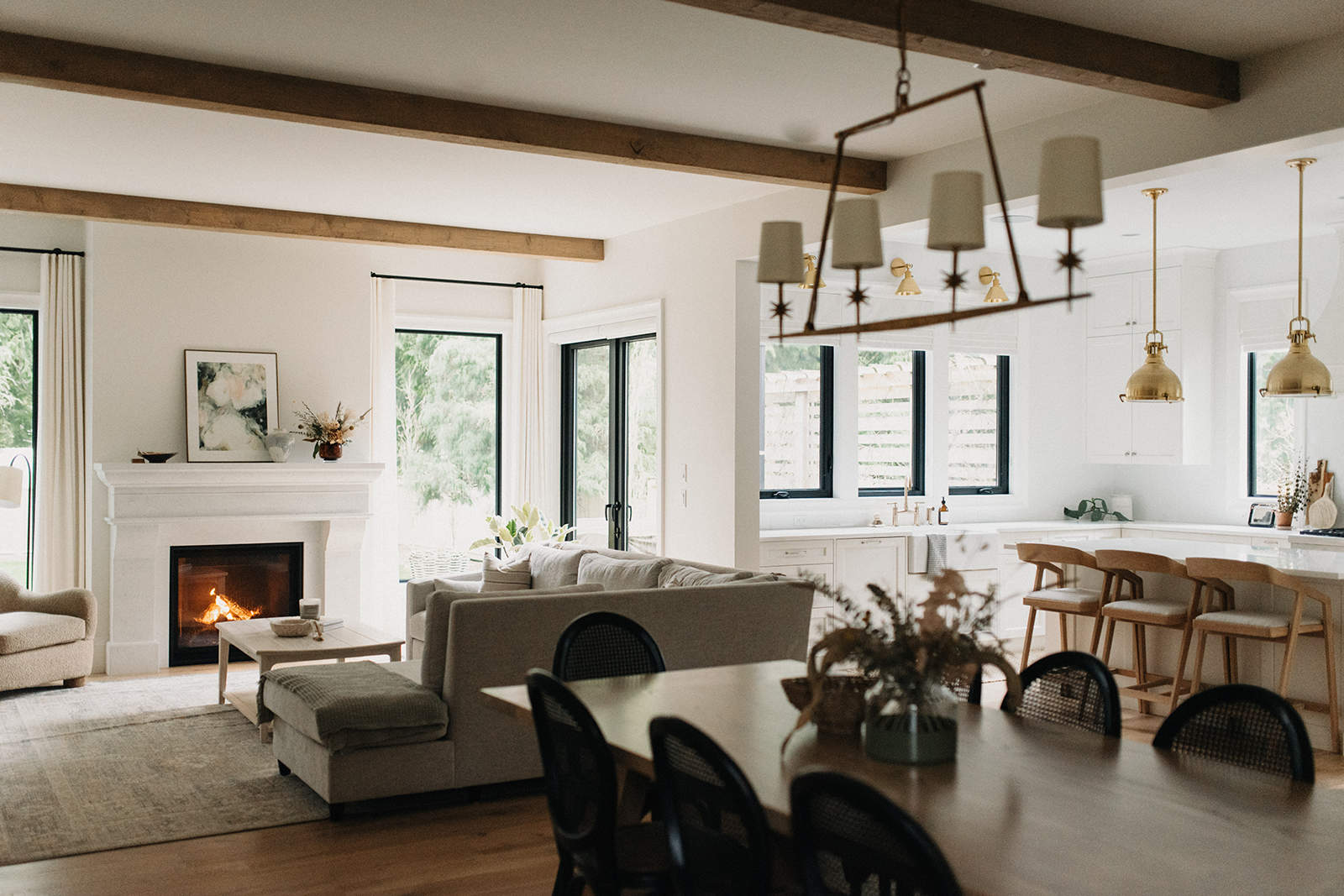 Open-concept floor plan connecting a modern kitchen with island seating to the dining room and living space with a cozy fireplace.