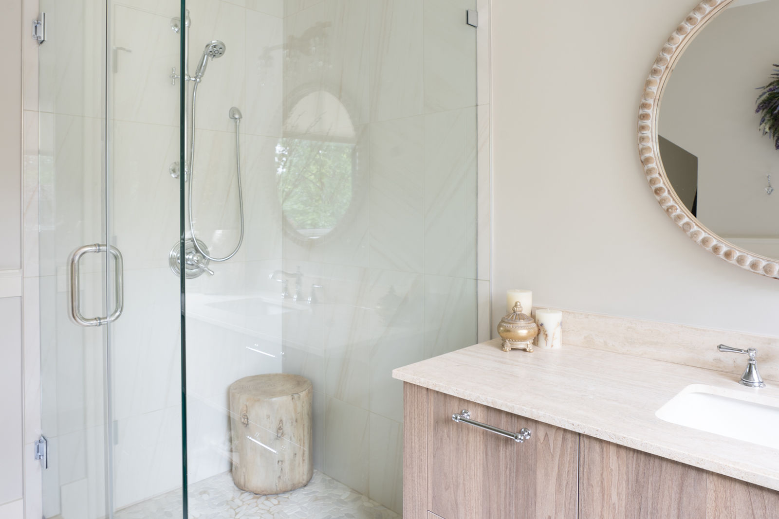 Modern walk-in shower featuring frameless glass doors, marble wall tile, handheld showerhead, and a wood vanity.